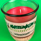 Recycled glass candle with red wax and white wick, on speckled cork base