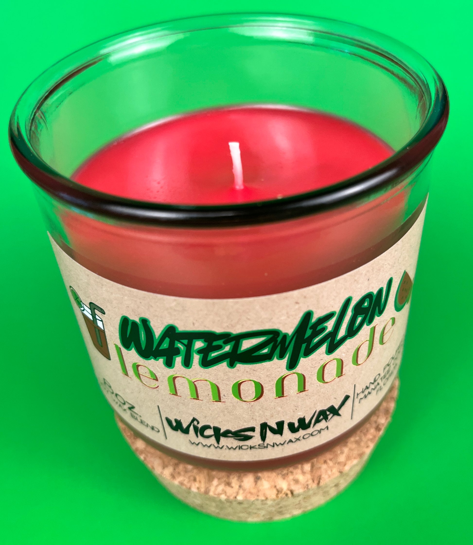 Recycled glass candle with red wax and white wick, on speckled cork base