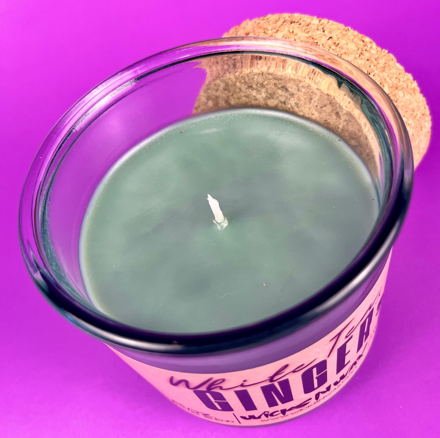 Recycled glass candle jar with visible wick and White Tea & Ginger label, cork base.